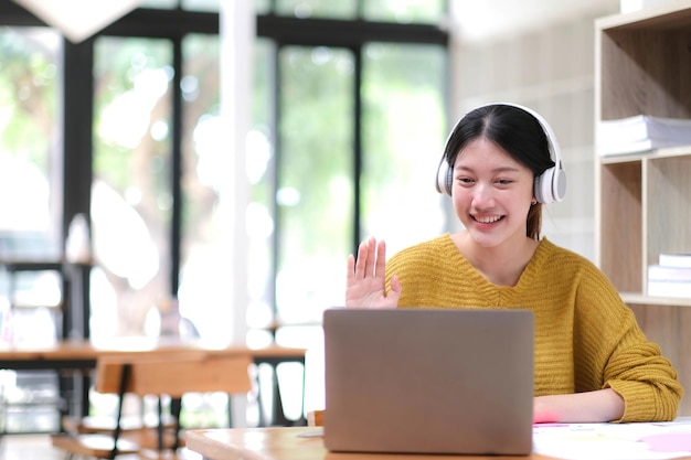 Asiatische Studentin Online-Lernklasse Studie Online-Videoanruf Zoom-Lehrer Fröhliches asiatisches Mädchen lernt die englische Sprache online mit einem Computer-Laptop