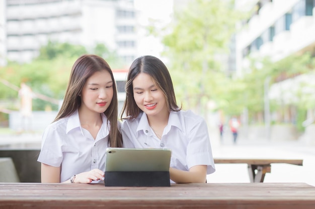 Asiatische studentinnen beraten sich gemeinsam und suchen mit dem tablet nach studienberichten