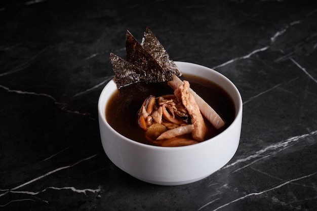 Asiatische Suppe mit Fleisch und Meeresfrüchten, Tellernahaufnahme auf dunklem Hintergrund, Gemüse
