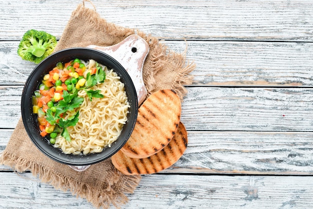 Asiatische Suppe mit Nudeln und Gemüse in einer Schüssel mit Toastbrot Diätkost Draufsicht Freier Kopierplatz