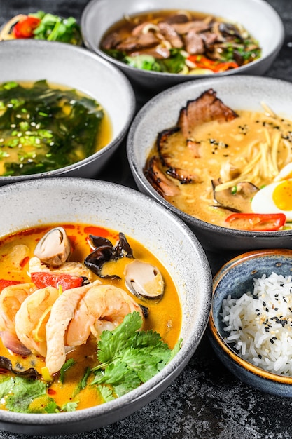 Asiatische Suppen, Miso, Ramen, Tom Yam, Pho Bo. Schwarzer Hintergrund. Draufsicht