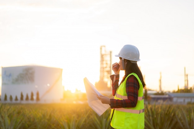 Asiatische Technikerin Wirtschaftsingenieurin mit Walkie-Talkie und Bluprint in der Ölraffinerie für Baustelle