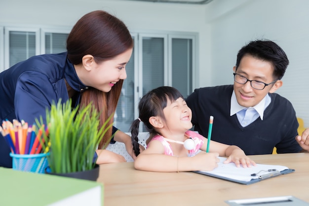 Asiatische thailändische Eltern unterrichten ihre Töchter mit einem lächelnden und glücklichen Gesicht. Im Konzept des Studiums zu Hause