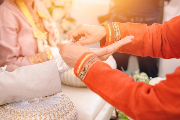 Asiatische thailändische Hochzeitskultur, die heilige Fäden am Handgelenk bindet und das Brautpaar segnet