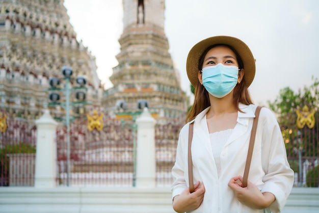 Asiatische Touristin mit Maske reist im Wat Arun in Bangkok, Thailand.