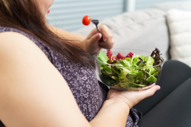 Asiatische übergewichtige Frau macht Diät. Gewichtsverlust beim Essen von frischem, frischem, hausgemachtem Salat. Konzept für gesunde Ernährung. Fettleibige Frau mit gewichtigem Diät-Lebensstil