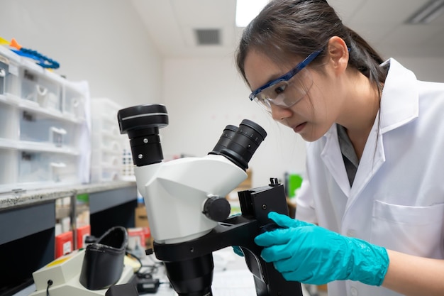 Asiatische Wissenschaftler, die im Labor arbeiten, Forscher forschen, um die Ergebnisse des Experiments zu finden. Ärzte testen Blut, um neue Stämme des Coronavirus durch Mikroskopie zu verhindern und zu zerstören