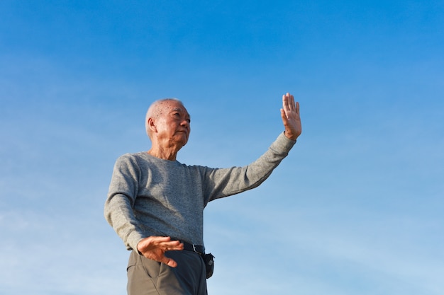 Asiatischer älterer alter Mann üben Taichi Chinese Kungfu am Strand