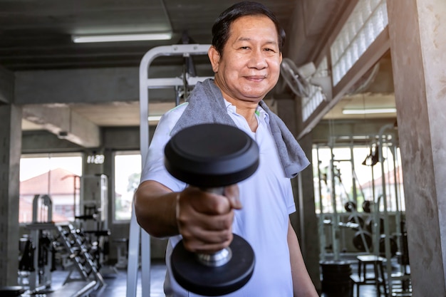 Asiatischer älterer Mann im Sportkleidungstraining mit Dummkopf an der Turnhalle.