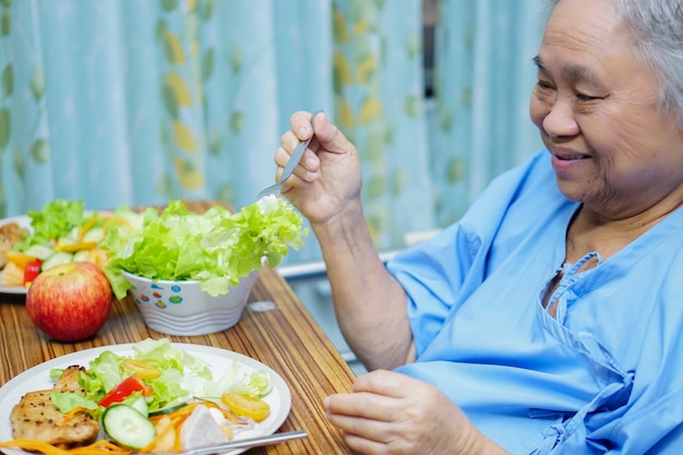 Asiatischer älterer Patient der alten Dame, der gesundes Lebensmittel des Frühstücks im Krankenhaus isst.