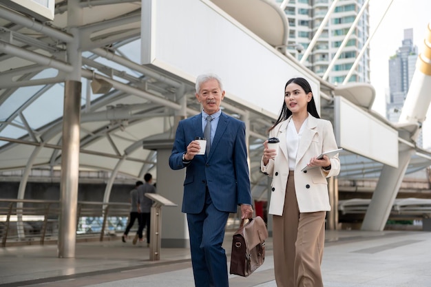 Asiatischer älterer reifer Geschäftsmann mittleren Alters und junge Geschäftsfrau, die eine Diskussion haben