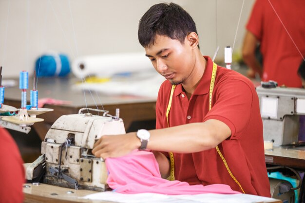 Asiatischer Arbeiter beim Nähen der Textilfabrik unter Verwendung des industriellen Nähens