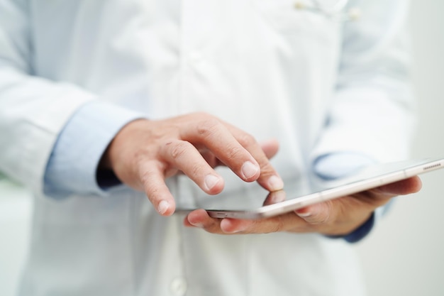 Asiatischer Arzt, der Tablet-Computer verwendet, um den Patientenbericht zu lesen, zu überprüfen und online im Krankenhaus nach einer Lösung für die medizinische Behandlung zu suchen