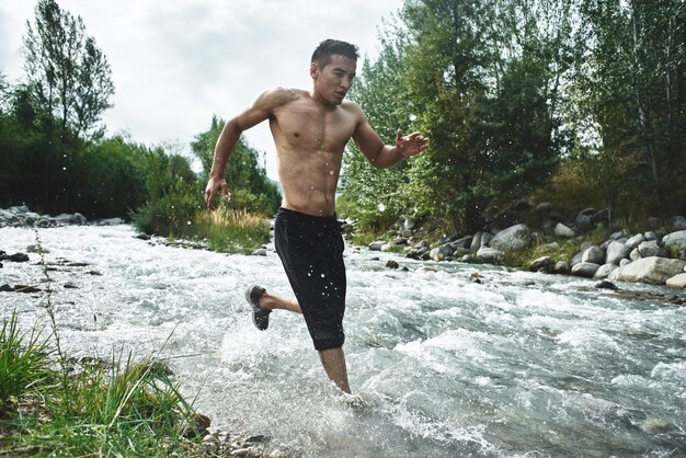 Asiatischer Athlet bei einem morgendlichen Lauf auf dem Fluss, kasachischer Jogger in der Natur aus nächster Nähe