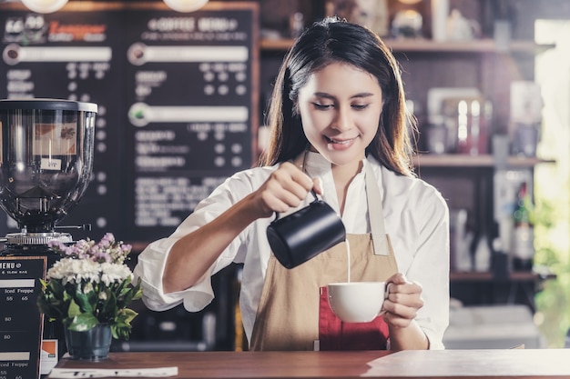 Asiatischer Barista, der eine Tasse Kaffee Espresso mit Latte oder Cappuccino für den Kunden zubereitet