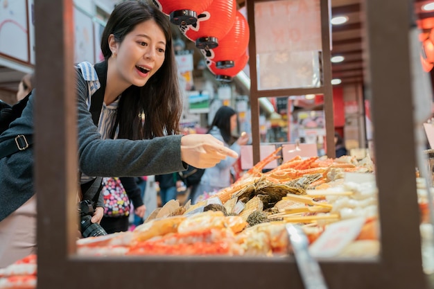 asiatischer besucher, der frische lebensmittel an straßenmarktständen findet. auf dem traditionellen japanischen Markt.