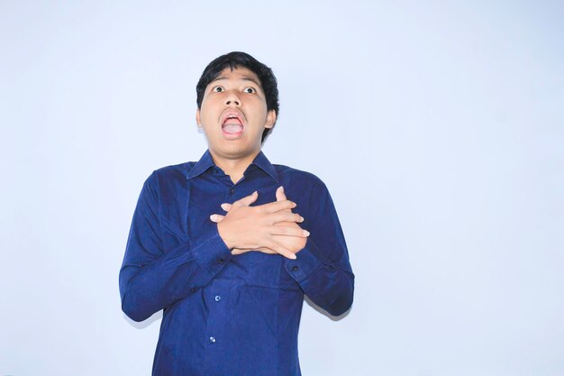 Asiatischer Büroangestellter schreit und berührt seine Brust und leidet an einem Herzinfarkt, der ein dunkelblaues Hemd trägt