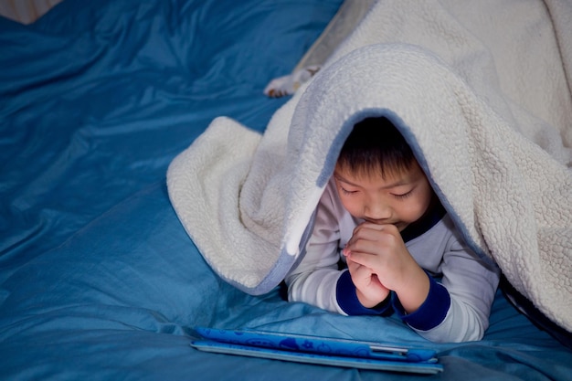 Asiatischer chinesischer Junge, der Smartphone spielt, Kind benutzt Telefon und Spiel, süchtiges Spiel und Cartoon