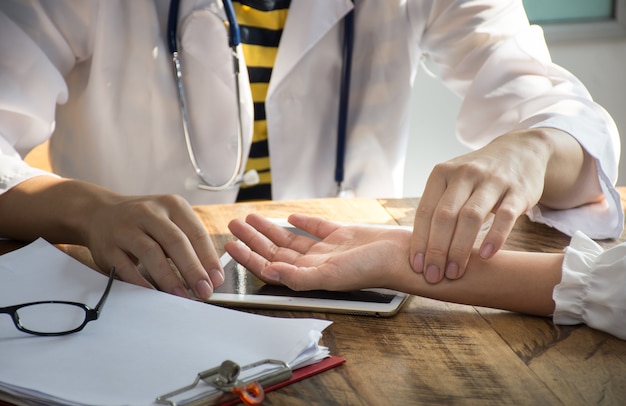 Asiatischer Doktor der Nahaufnahme überprüft den Impuls der Geduld durch Finger