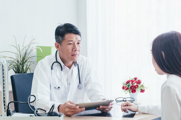 Asiatischer Doktor und Patient besprechen sich