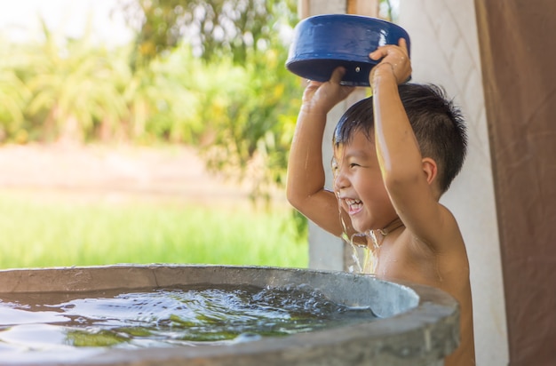 Asiatischer Dorf-armer Junge nimmt ein Bad vom Dorfwasserbrunnen.