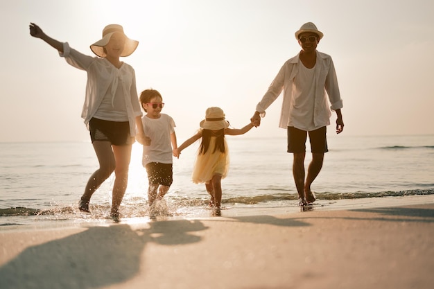 Asiatischer Familienurlaub Glückliche Familie, die abends am Strand läuft Rückansicht