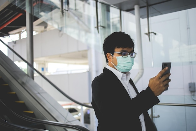 Asiatischer Freiberufler mit OP-Maske, der morgens in der U-Bahn zur Arbeit geht