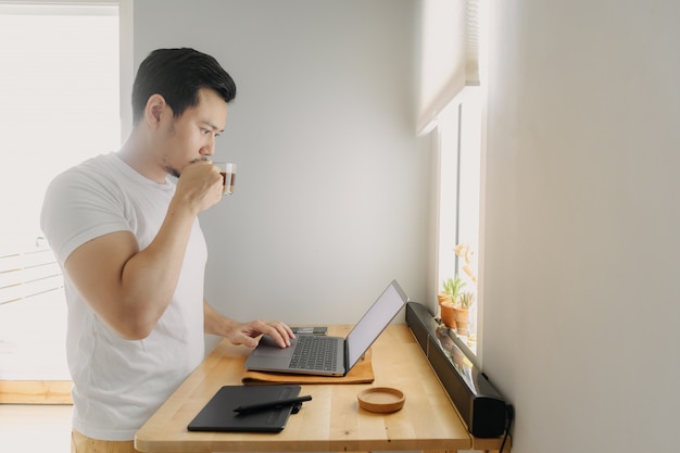 Asiatischer Freiberuflermann denkt und arbeitet an seinem Laptop.