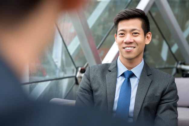 Asiatischer Geschäftsmann, der am Büroaufenthaltsraum sitzt