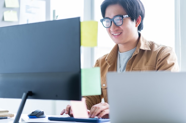 Asiatischer Geschäftsmann, der mit Computer im Büro arbeitet