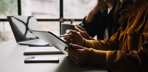 Asiatischer Geschäftsmann und Geschäftsfrau des Unternehmers, die neues Geschäftsprojekt in der Tablette im modernen Meeting im modernen Büro besprechen Asiatisches Business-Casual-Konzept