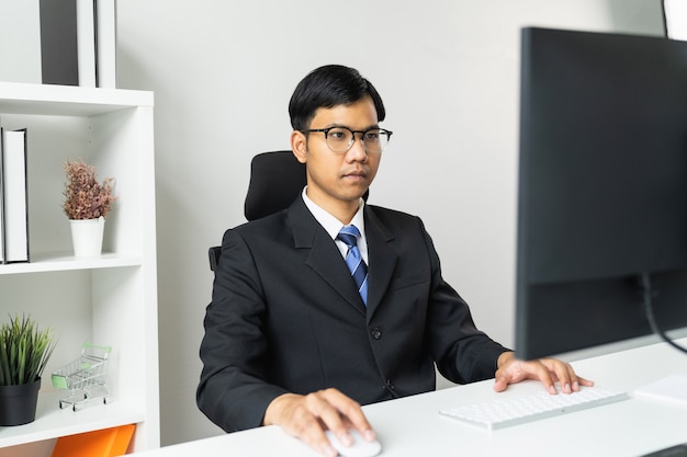 Asiatischer Geschäftsmann unter Verwendung des Computers auf dem Tisch im Büro.