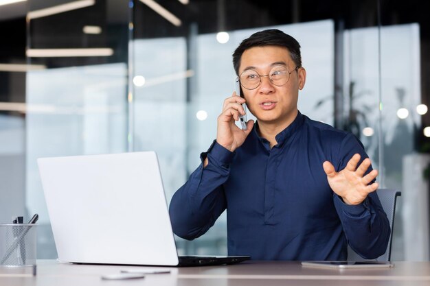 Asiatischer geschäftsmannstudent des jungen mannes, der am telefon mit kunden und partnern spricht, die in sitzen