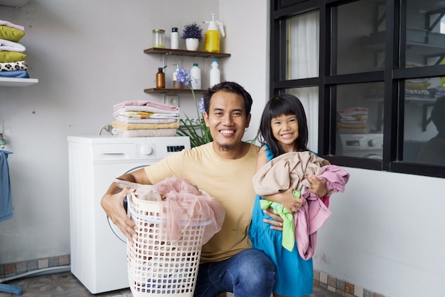 Asiatischer glücklicher Familienvatervater-Hausbesitzer und Kindertochter in der Wäscherei mit Waschmaschine zusammen