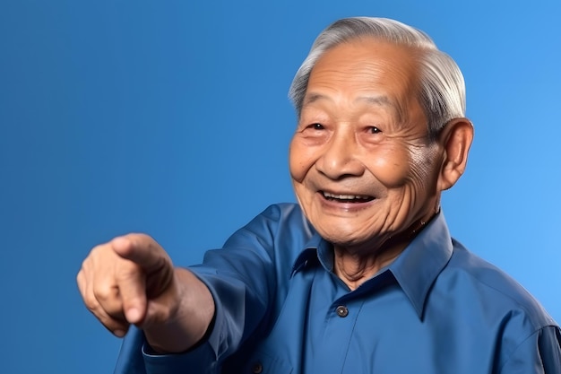 Asiatischer Großvater schaut und lächelt mit erhobenem Zeigefinger auf blauem Hintergrund.