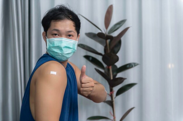 Asiatischer gutaussehender Mann mit geimpftem Arm Lassen Sie sich zum Schutz vor COVID19 impfenAntivirus-Corona-Virus-Konzept