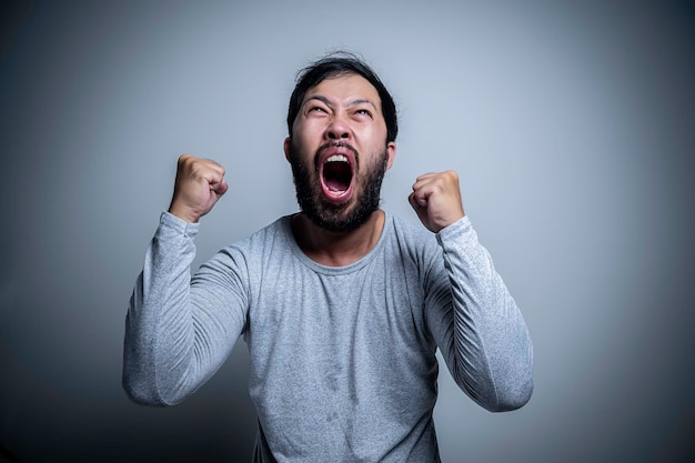 Asiatischer gutaussehender Mann wütend auf weißem HintergrundPorträt des jungen männlichen Stresskonzepts