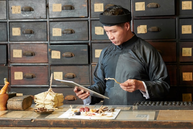 Asiatischer Heilpraktiker mit Tablette