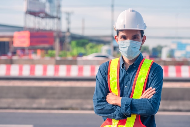 Asiatischer Ingenieur, der im Freien vor Ort steht und selbstbewusste Ingenieurkonstruktion postet