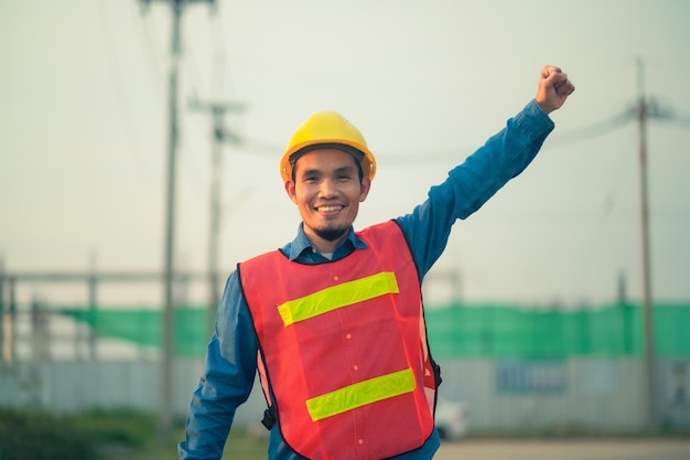 Asiatischer Ingenieur, der im Freien vor Ort steht und zuversichtlich ist, Ingenieurbau, glücklicher Joberfolg bei der Zielplanung