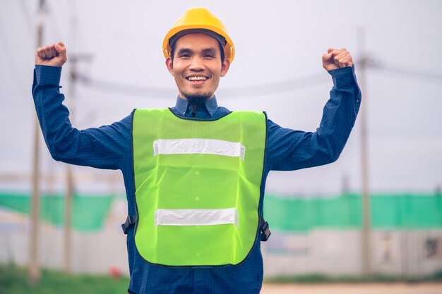 Asiatischer Ingenieur, der im Freien vor Ort steht und zuversichtlich ist, Ingenieurbau, glücklicher Joberfolg bei der Zielplanung