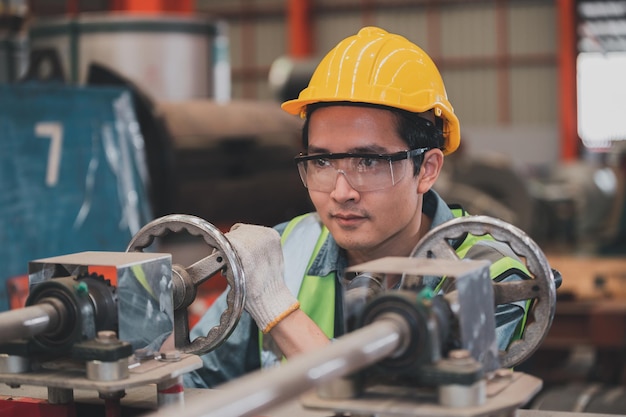 Asiatischer Ingenieur, der in einer Fabrik mit Maschinentechniker-Fähigkeiten arbeitet, arbeitet in der industriellen Produktion