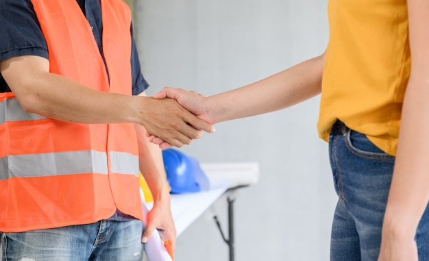 Asiatischer Ingenieur und Architekt Handschlag auf der Baustelle. Teamwork und erfolgreiches Siedlungsbauprojekt