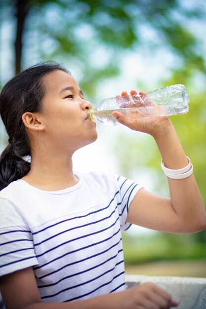 asiatischer Jugendlicher, der Wasser von der Plastikflasche trinkt