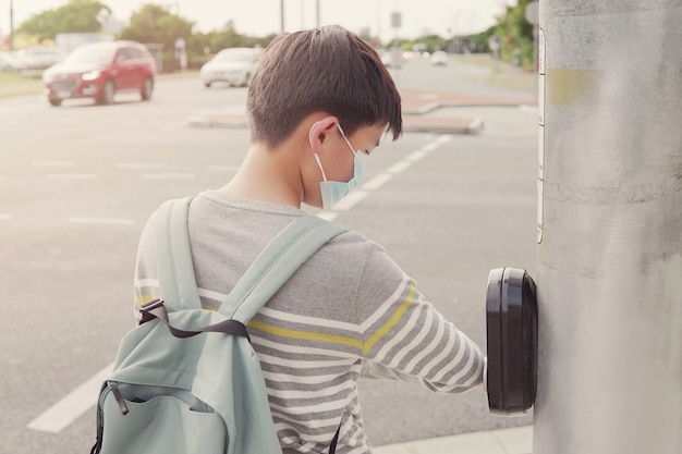 asiatischer jugendlicher zwischen jugendlicher Junge, der seinen Ellbogen benutzt, der Ampelknopf drückt