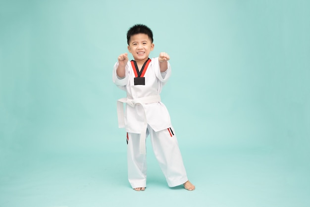 Asiatischer Junge in einem Taekwondo-Anzug, der Kampfkunstbewegungen einzeln auf grünem Hintergrund macht