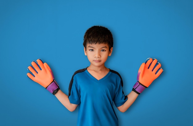 Asiatischer Junge ist ein Fußballtorhüter, der Handschuhe trägt und seine Hand isoliert auf Weiß ausbreitet