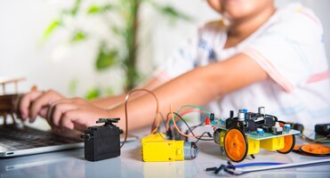 Asiatischer junge lernt codierung und programmierung mit laptop für arduino-roboterauto
