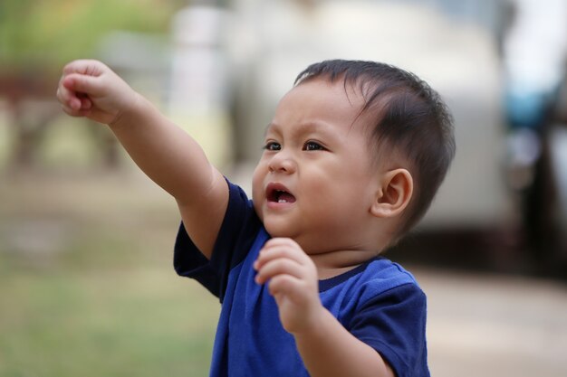 Asiatischer Junge lernt im Garten laufen.