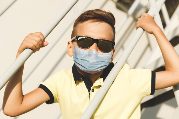 Asiatischer Junge mit Sonnenbrille auf der Treppe in einem gelben T-Shirt und Jeans